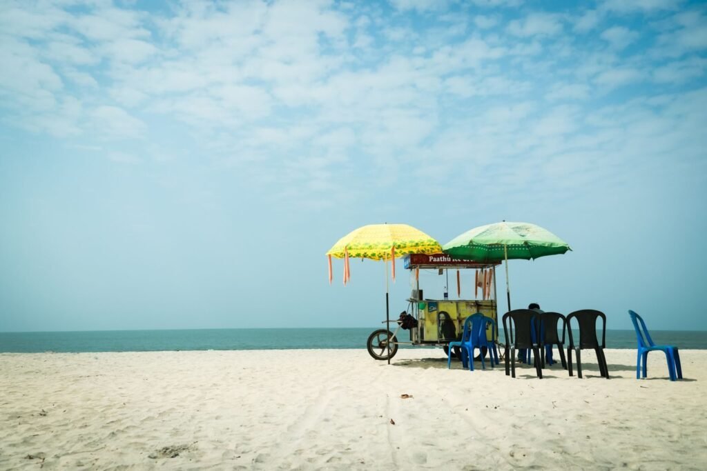 Idyllic Alappuzha beach with colorful umbrella cart and chairs, perfect serene getaway.